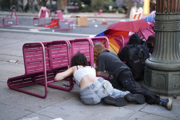 Protesters take cover behind chairs near the Metropolitan Detention Center in downtown Los Angeles, Sunday, June 8, 2025, following last night's immigration raid protest. (AP Photo/Eric Thayer) AP PHOTOS: Protesters clash with law enforcement in Los Angeles